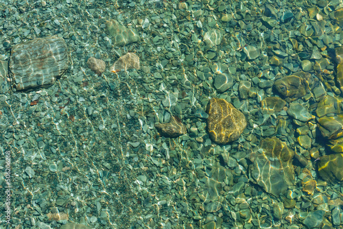 Turquoise transparent water with pebbles at the bottom. Beautiful background.