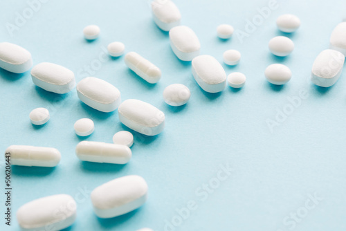 White pills on a pastel background. Capsules and round pills close-up. Healthcare and medicine.