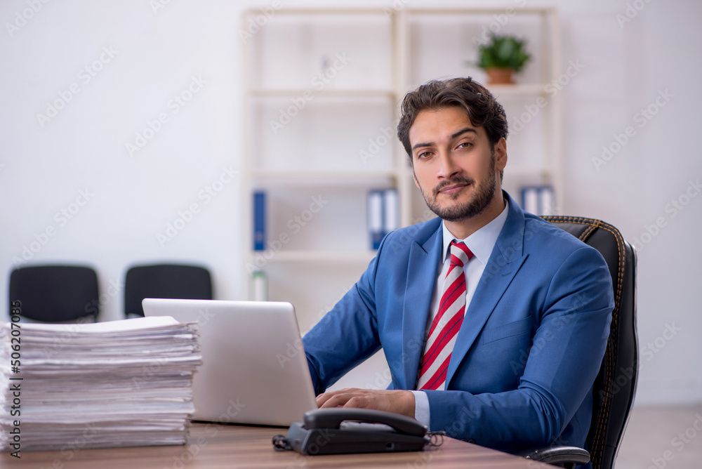 Young male employee and too much work in the office Young male employee and too much work in the office