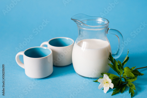 Milk in a jug and two cups on a blue background