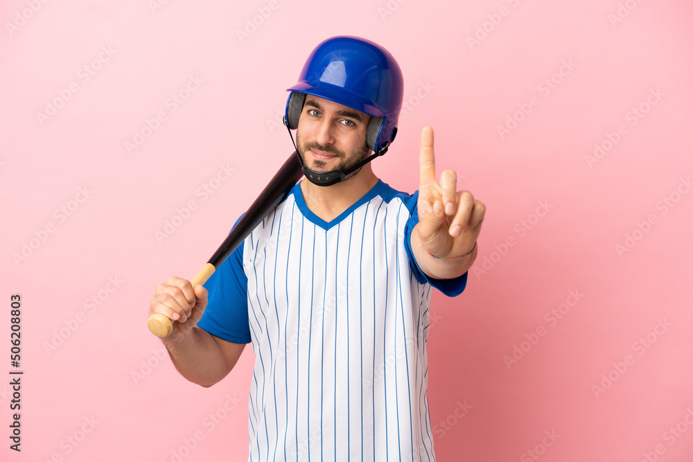 Baseball player with helmet and bat isolated on pink background showing and lifting a finger Baseball player with helmet and bat isolated on pink background showing and lifting a finger
