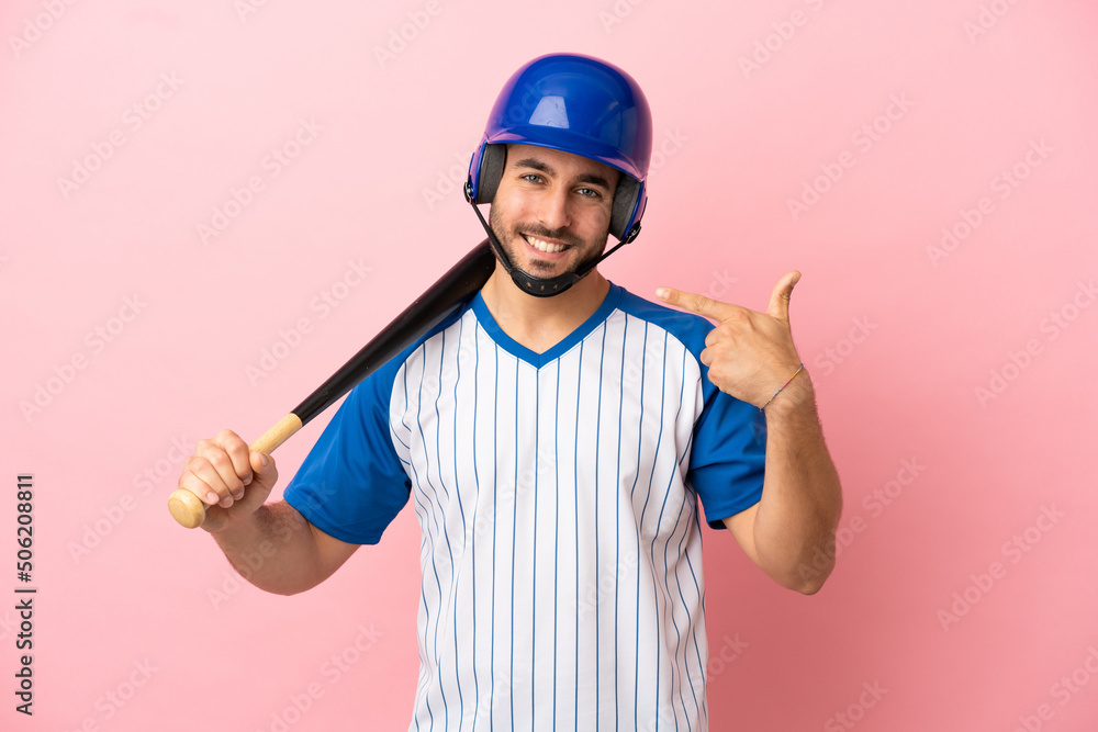 Baseball player with helmet and bat isolated on pink background giving a thumbs up gesture