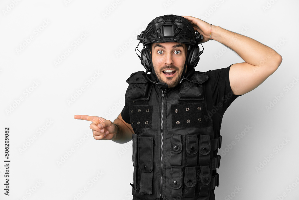 Young caucasian swat isolated on white background surprised and pointing finger to the side Young caucasian swat isolated on white background surprised and pointing finger to the side