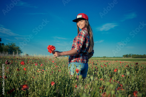 girl in the poppy field. The girl scatters over the petals of red flowers. A girl with long hair rejoices life. Summer Travel and Freedom