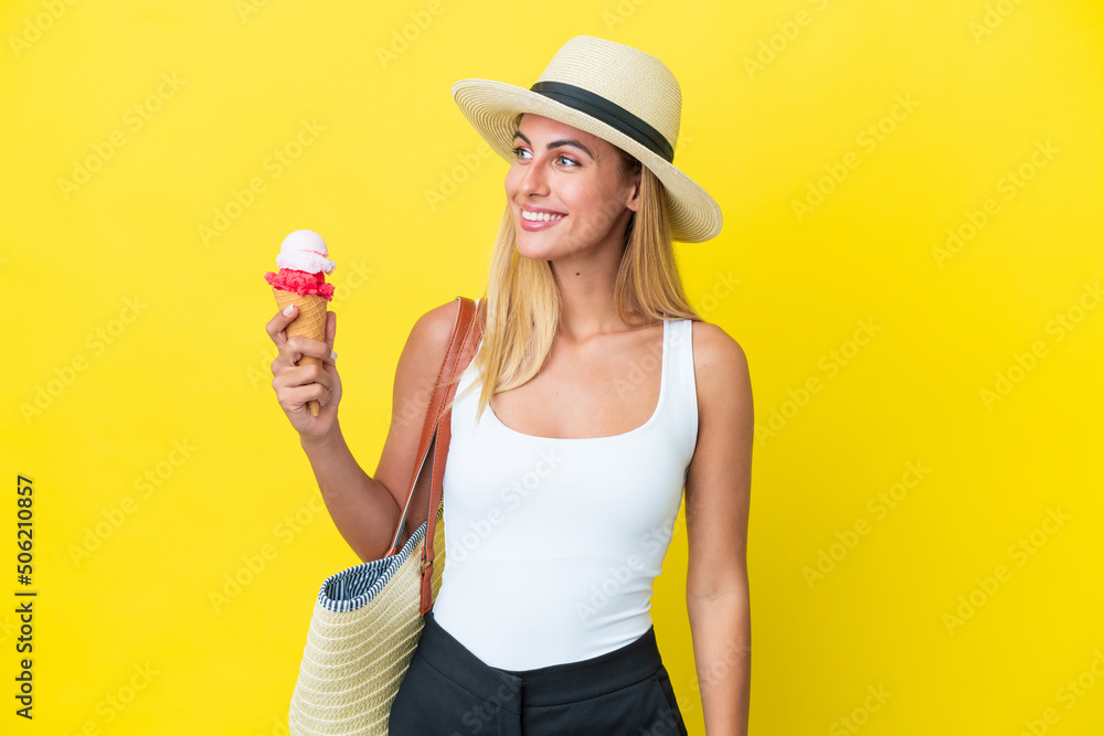 Blonde Uruguayan girl in summertime holding ice cream isolated on yellow background looking to the side and smiling Blonde Uruguayan girl in summertime holding ice cream isolated on yellow background looking to the side and smiling