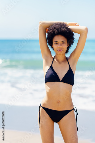 African American woman with slim body wearing bikini on a tropical beach.