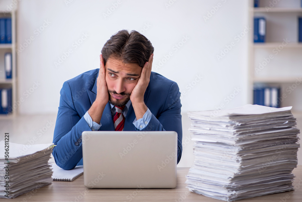Young male employee and too much work in the office Young male employee and too much work in the office