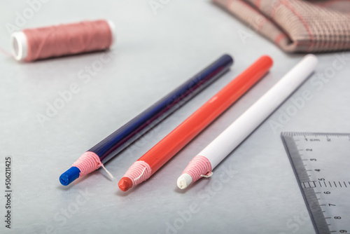 Multi-colored tailor's markers and sewing accessories lie on the table