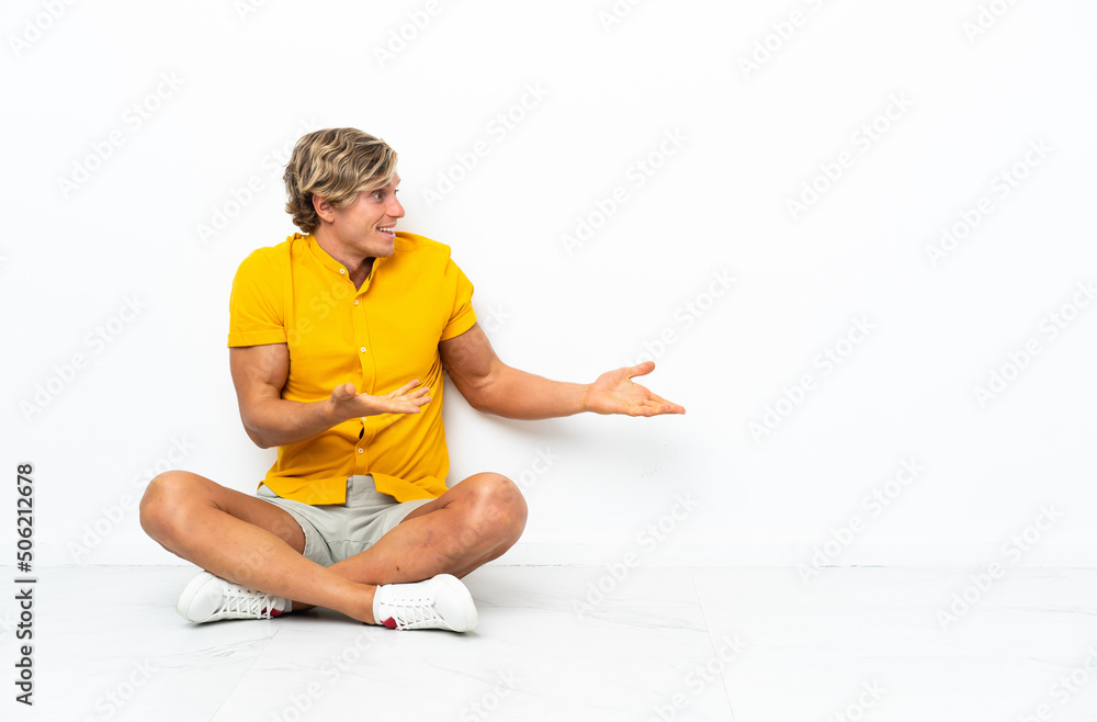 Fototapeta premium Young English man sitting on the floor with surprise expression while looking side