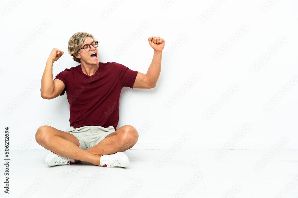 Fototapeta premium Young English man sitting on the floor celebrating a victory
