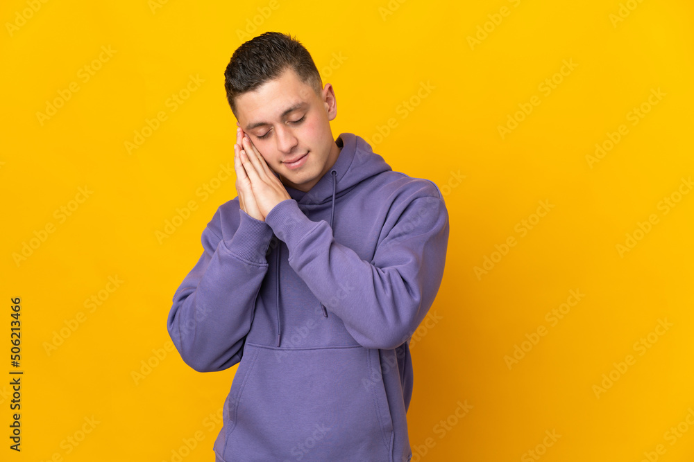 Young caucasian man isolated on yellow background making sleep gesture in dorable expression Young caucasian man isolated on yellow background making sleep gesture in dorable expression
