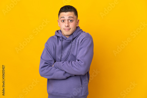 Young caucasian man isolated on yellow background making doubts gesture while lifting the shoulders