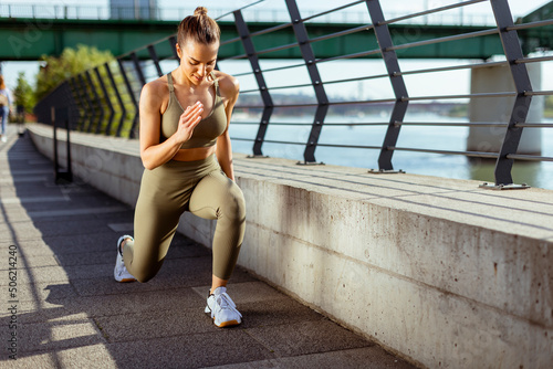 Young woman in sportswear stretching on a river promenade