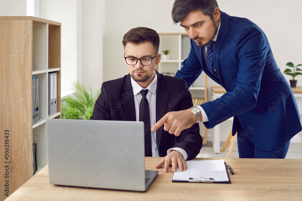 Lawyers working in office. Serious lawyers are working on lawsuit using laptop and Internet to search for case data. Two male colleagues of law firm employees in suits are working on one legal case. Lawyers working in office. Serious lawyers are working on lawsuit using laptop and Internet to search for case data. Two male colleagues of law firm employees in suits are working on one legal case.