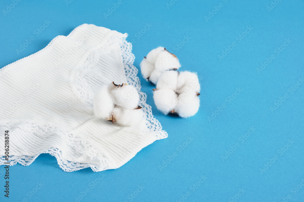 Obraz premium woman pants and cotton flowers on blue background copy space