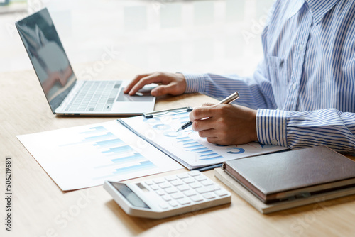 Close up hands of business man using a calculator to calculate expenses from receipts placed on the table. tax concept.