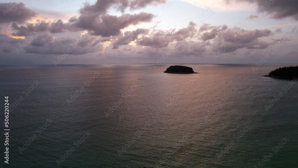 View from the top of Phuket island and the sea. It's raining in the distance, grey clouds. In places, you can see the blue sky and sunset. There is lonely island covered with trees. Boats are sailing View from the top of Phuket island and the sea. It's raining in the distance, grey clouds. In places, you can see the blue sky and sunset. There is lonely island covered with trees. Boats are sailing