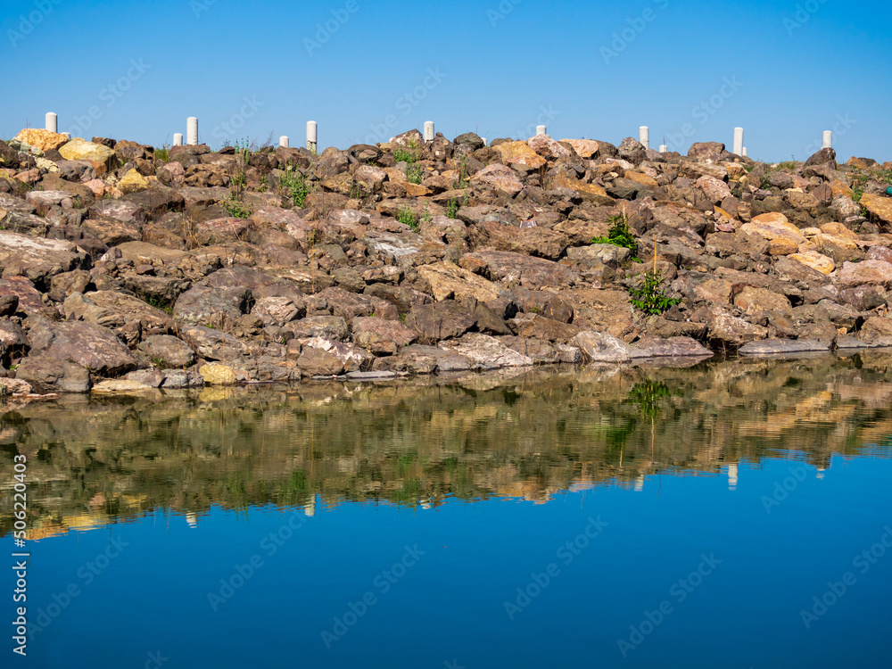 Reflection of rocks by the lake on the water surface.