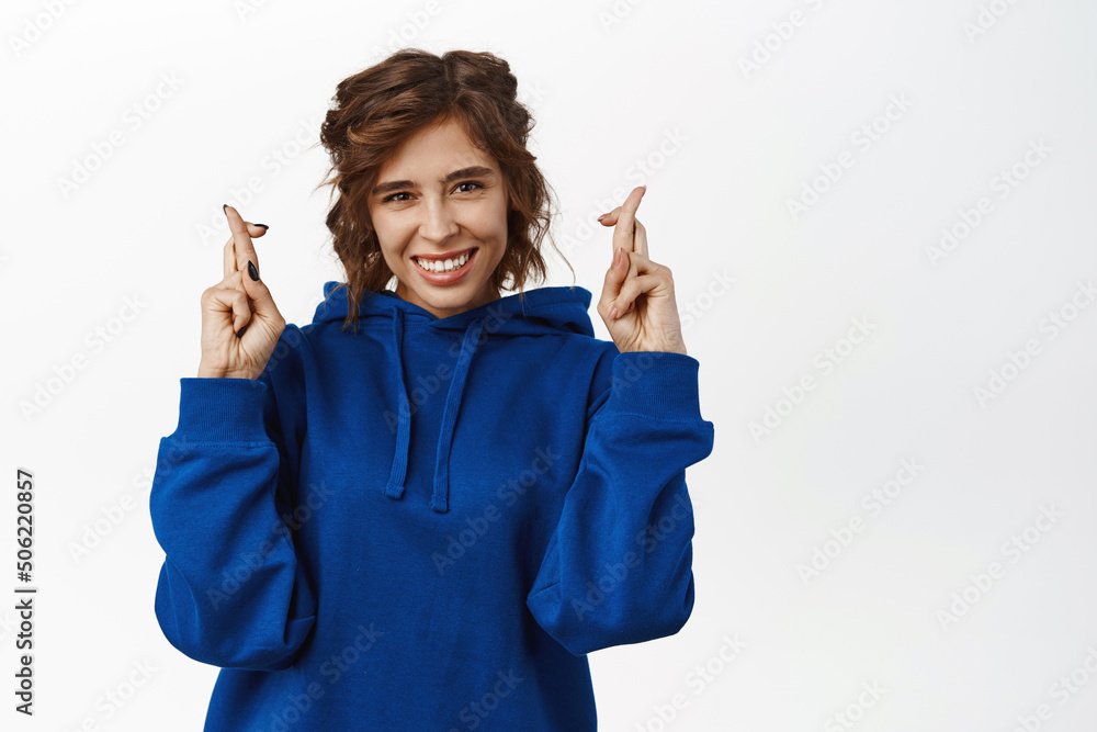 Portrait of smiling brunette woman cross fingers, praying, anticipating good news, yearning and waiting for something, making wish, standing over white background Portrait of smiling brunette woman cross fingers, praying, anticipating good news, yearning and waiting for something, making wish, standing over white background
