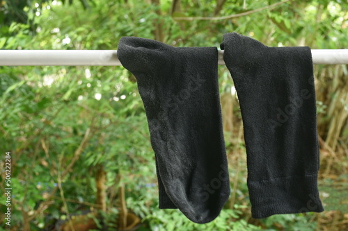 Obraz na plátně old black sock hanging for drying on cloth line in backyard garden