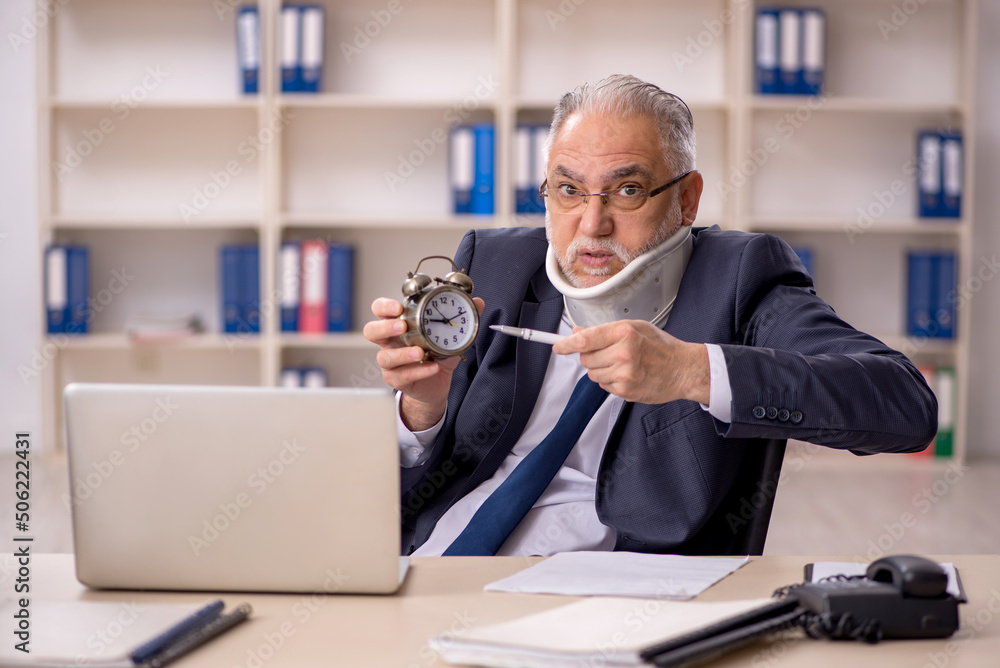 Old male employee after accident sitting at workplace Old male employee after accident sitting at workplace