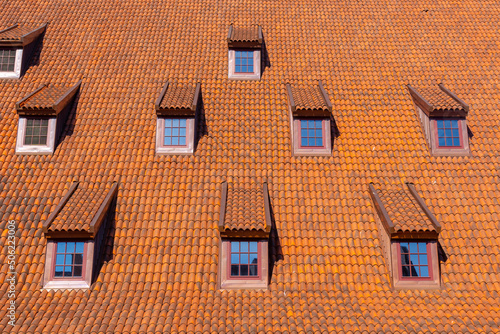 Many small windows on a red roof covered with tiles in the old town of Gdansk