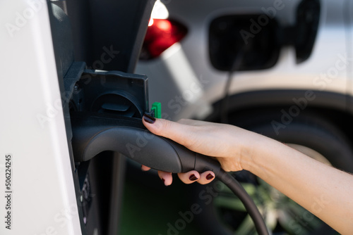 Woman holding plug of electric car charging station  © scharfsinn86