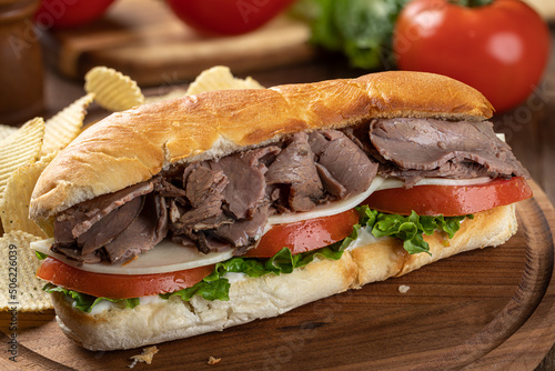 Submarine sandwich with roast beef, cheese, tomato and lettuce photo