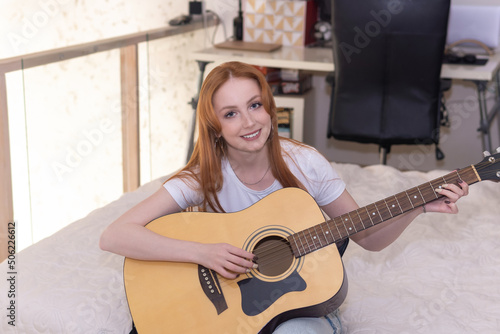 young woman playing acoustic guitar at home