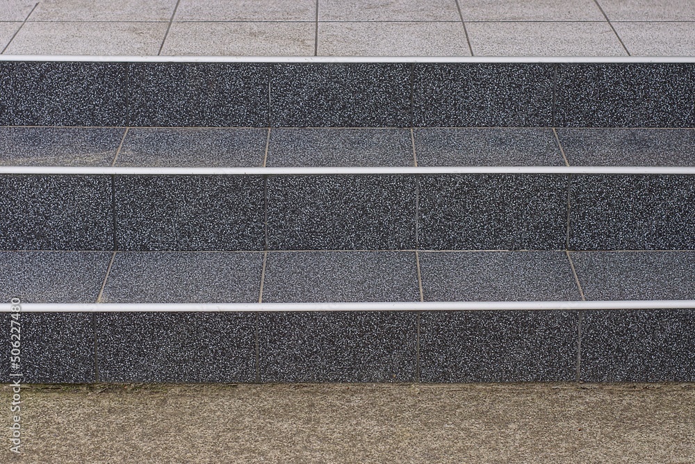 part of a large stone threshold with black steps on gray asphalt in the street