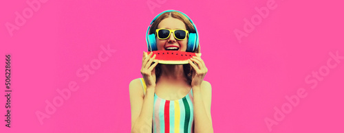 Summer colorful portrait of cheerful happy smiling young woman model posing in headphones listening to music with juicy slice of watermelon on pink background, blank copy space for advertising text