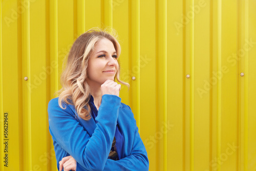 Beautiful blonde woman on yellow background looking forward and thinking