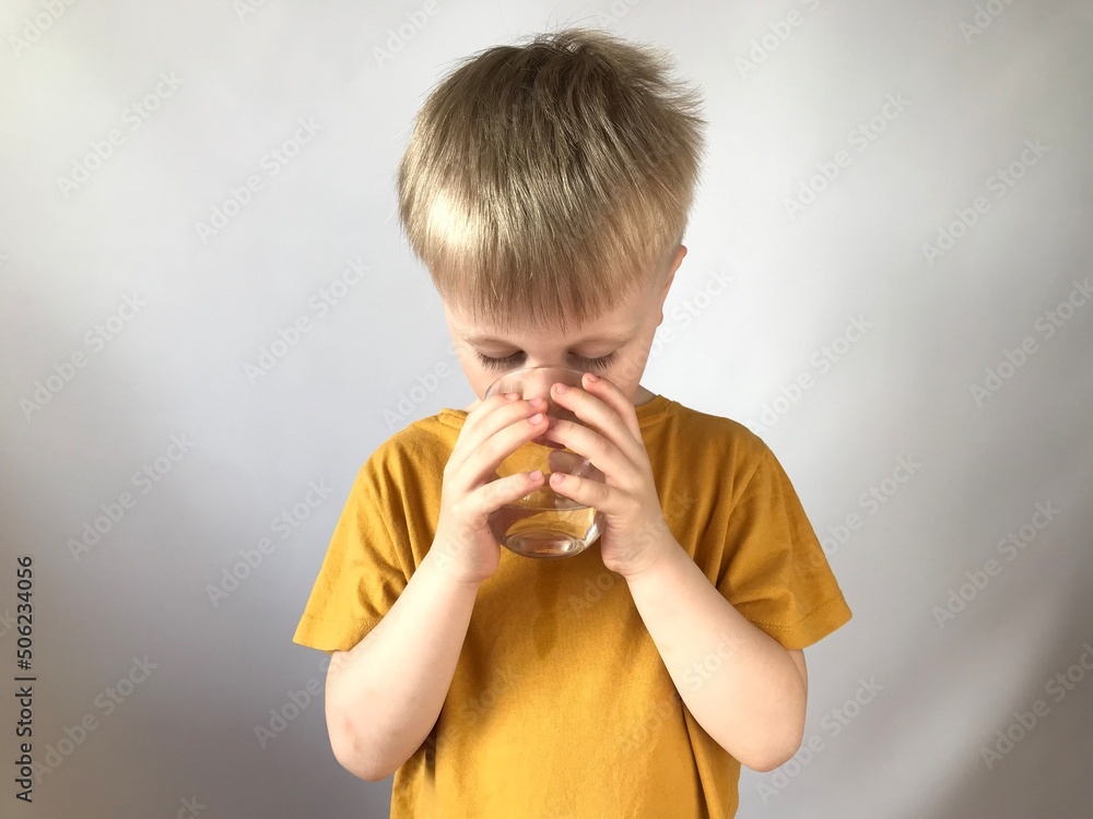 little boy in a yellow T-shirt drinks water little boy in a yellow T-shirt drinks water