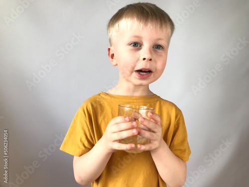 little boy in a yellow T-shirt drinks water