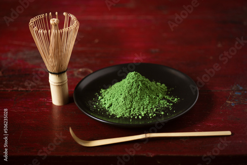 Matcha green tea with bamboo whisk on wooden table