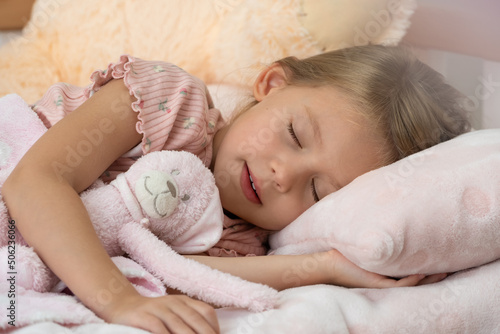 Little child sleeps at home in bed with toy. Child in dream hugs teddy bear. Orthopedic pillow, mattress and healthy sleep concept © Belkina Margarita