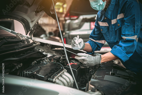 Car care maintenance and servicing, Close-up hand technician auto mechanic checking inspection list after repairing change spare part car engine problem and car insurance service.