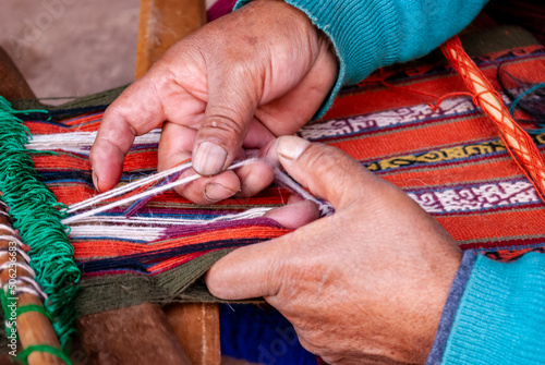 Close up of weaving textiles using manual loom in Peru photo