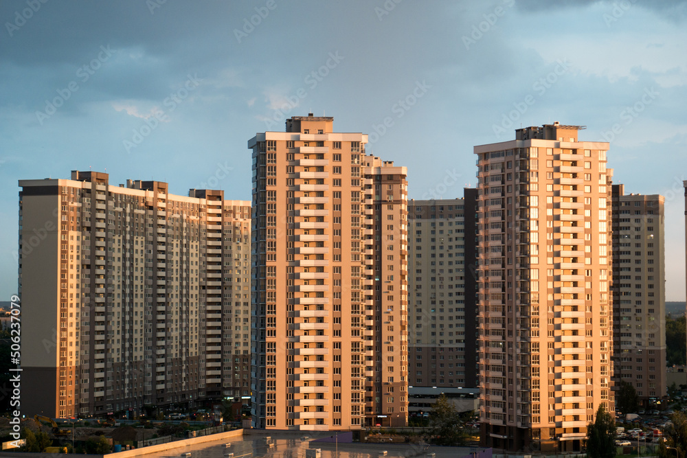 Modern residential complex on the background of cloudy clouds. Weather before rain. Dark sky over city district with high-rise buildings. Aerial view of multi-storey buildings.