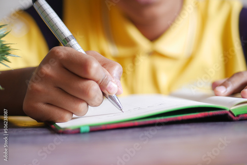 child hand writing on notepad shile sitted  photo