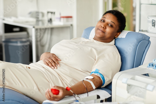 Foto Portrait of smiling woman giving blood while laying in chair at blood donation c