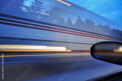 A blurred image of a large bus from a car window due to speed. The vehicle was moving towards the highway at high speed.