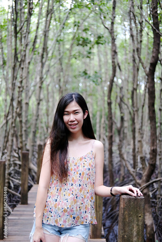 Pretty Asain girl is smiling and standing on wooden bridge in the tropical mangrove forest at Thailand.