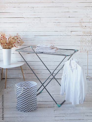 clean, freshly laundered linen and a white shirt hang on a metal dryer in a bright room