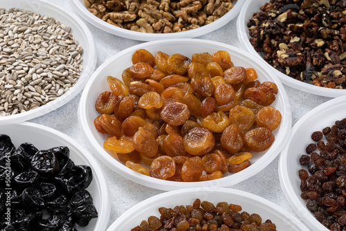 Various dried fruits dried apricots nuts and sunflower seeds lie on round plates on a light background. The concept of a healthy healthy diet. Source of vitamins, vegetable proteins and fats, oils.