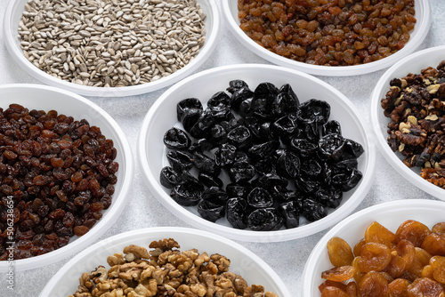 Various dried fruits, prunes, nuts and sunflower seeds lie on round plates on a light background. The concept of a healthy healthy diet. Source of vitamins, vegetable proteins and fats, oils.