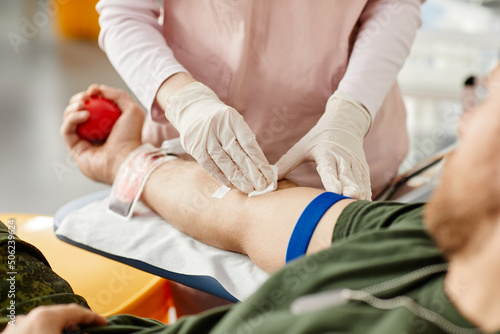 Close up of male donor giving blood at donation center with nurse helping, copy space