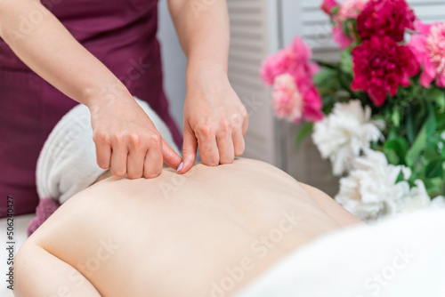 Womens hands do therapeutic neck massage for girl lying on couch in the massage spa. Body care, skin care.