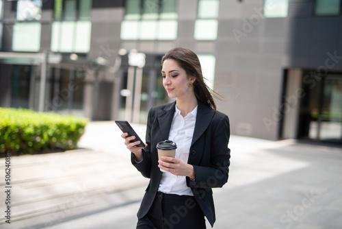 Businesswoman using her mobile phone while walking outdoor