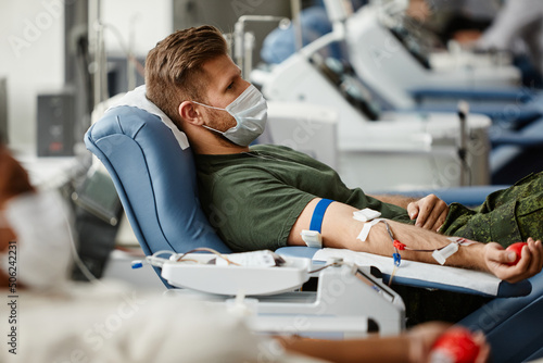 Foto Side view portrait of military soldier donating blood while lying in chair at do